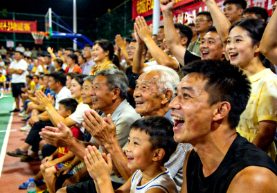 村BA观众群像特写，有老人、小孩和年轻人，大家表情专注而喜悦，共同为进球欢呼