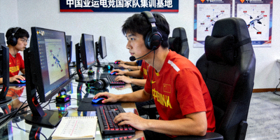 中国亚运电竞国家队集训基地训练照片，选手佩戴耳机专注屏幕
